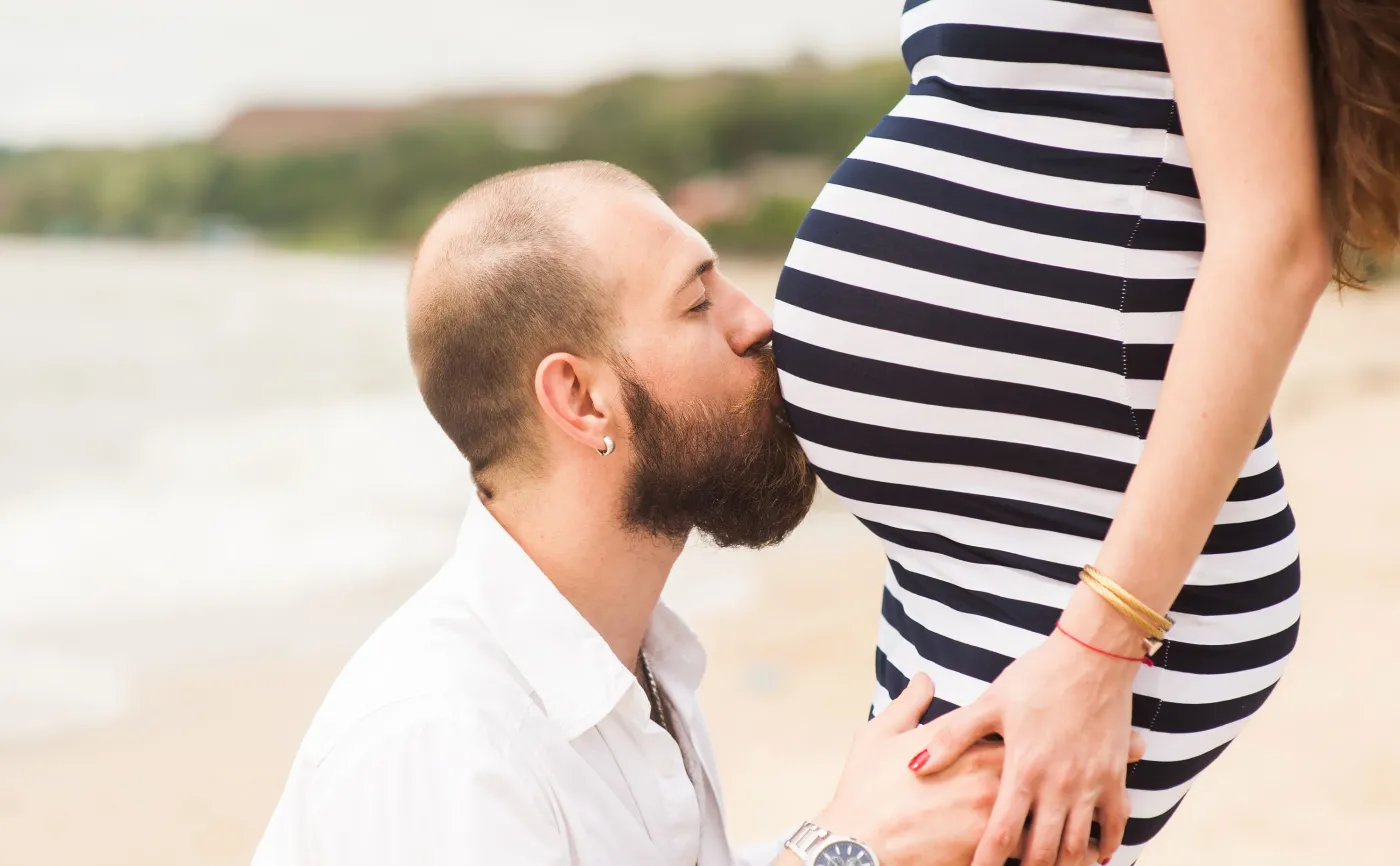 Mężczyzna całuje brzuch ciężarnej kobiety