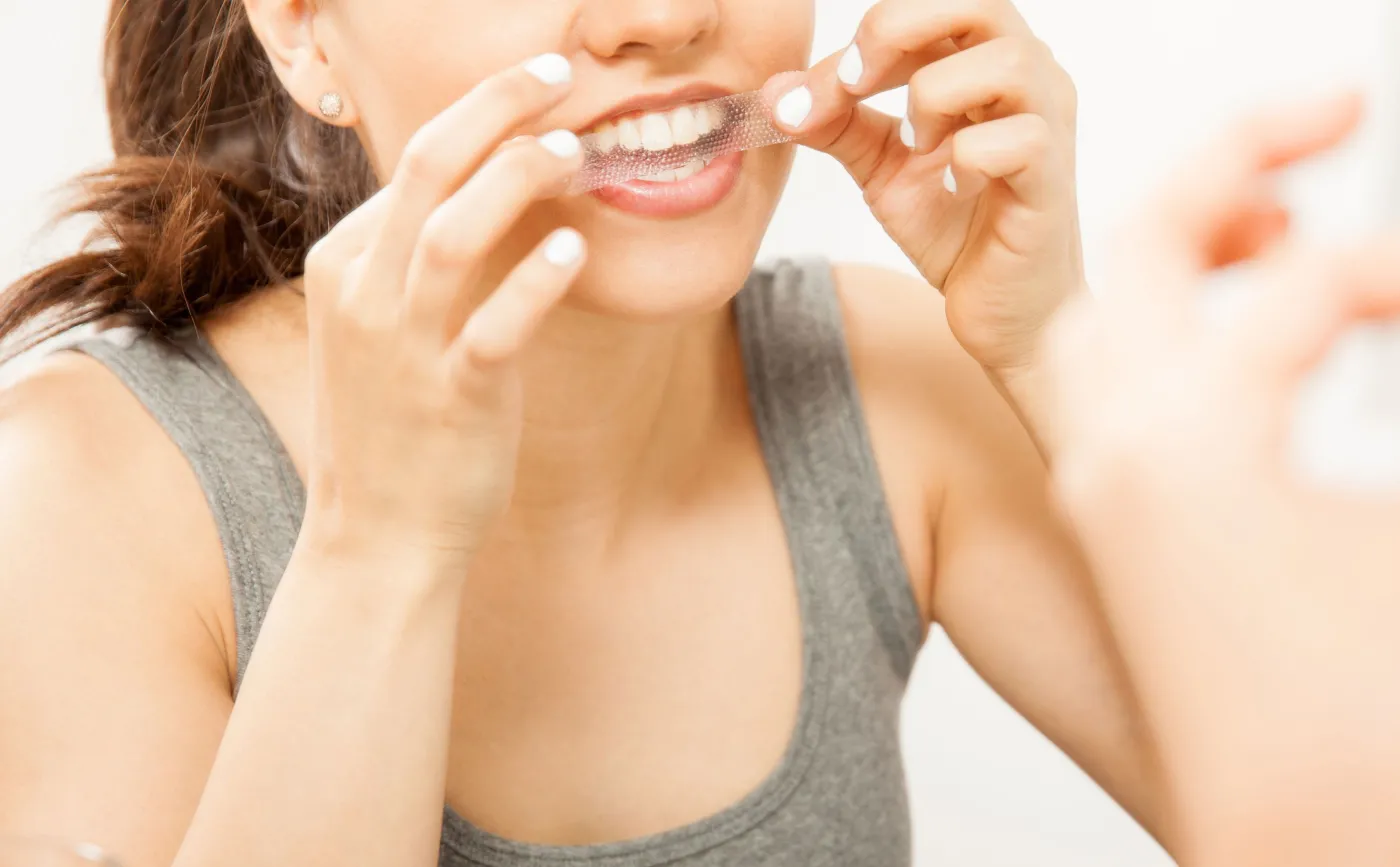 Kobieta używa pasków wybielających na zęby