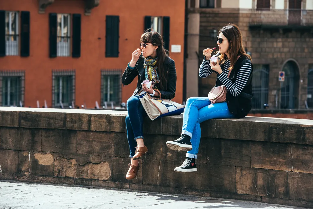 Turystki jedzą lody na zbytkowym moście we Florencji