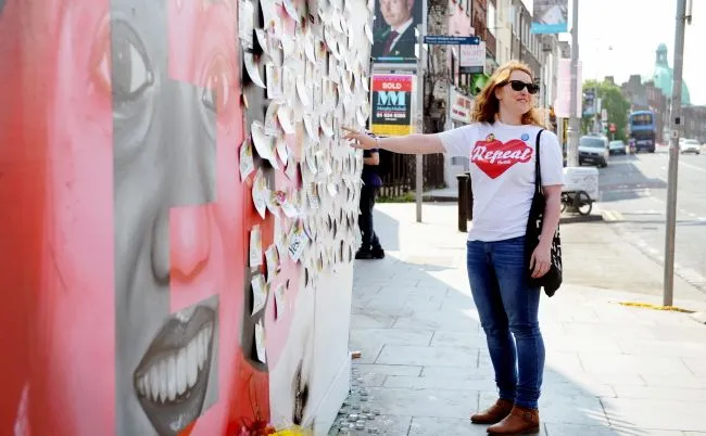 Zwolenniczka liberalizacji prawa aborcyjnego przed muralem w Dublinie przedstawiającym hinduską obywatelkę Irlandii Savitę Halappanavar, która zmarła w rezultacie komplikacji porodowych i została twarzą protestu na rzecz praw kobiet