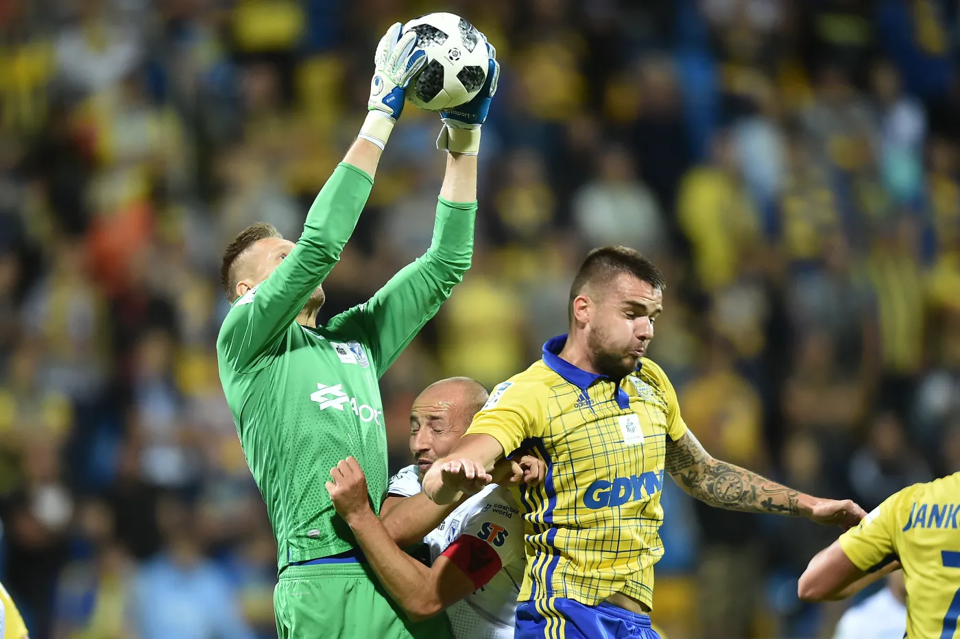 Zawodnicy Arki Gdynia Aleksandar Kolev (P) i bramkarz Matus Putnoscky (L) oraz Łukasz Trałka (2-L) z Lecha Poznań 