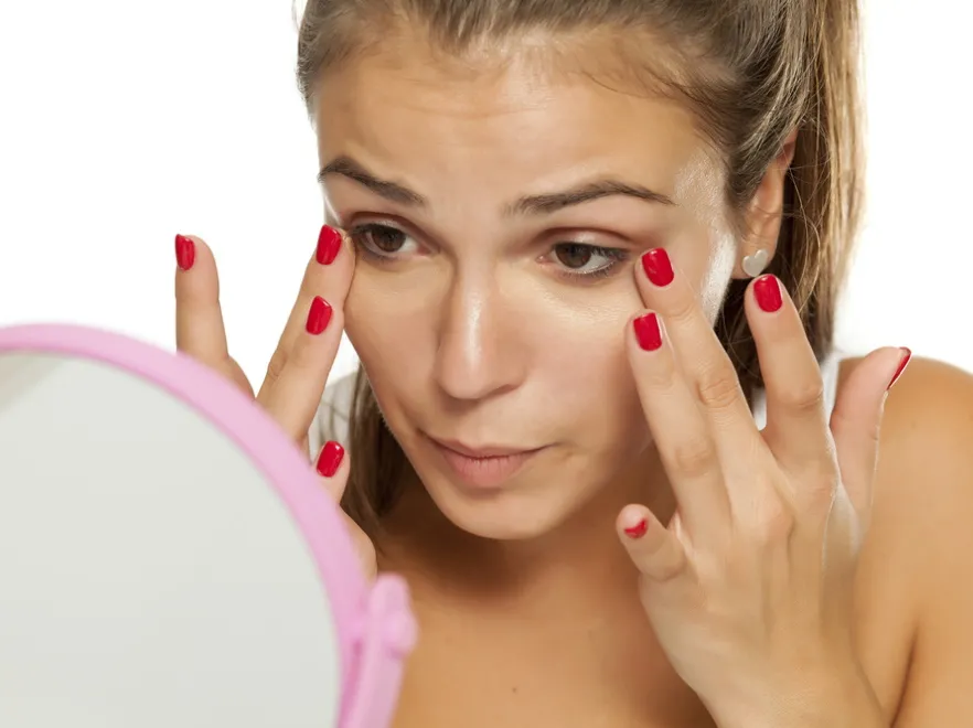 Kobieta robi makijaż przed lustrem.