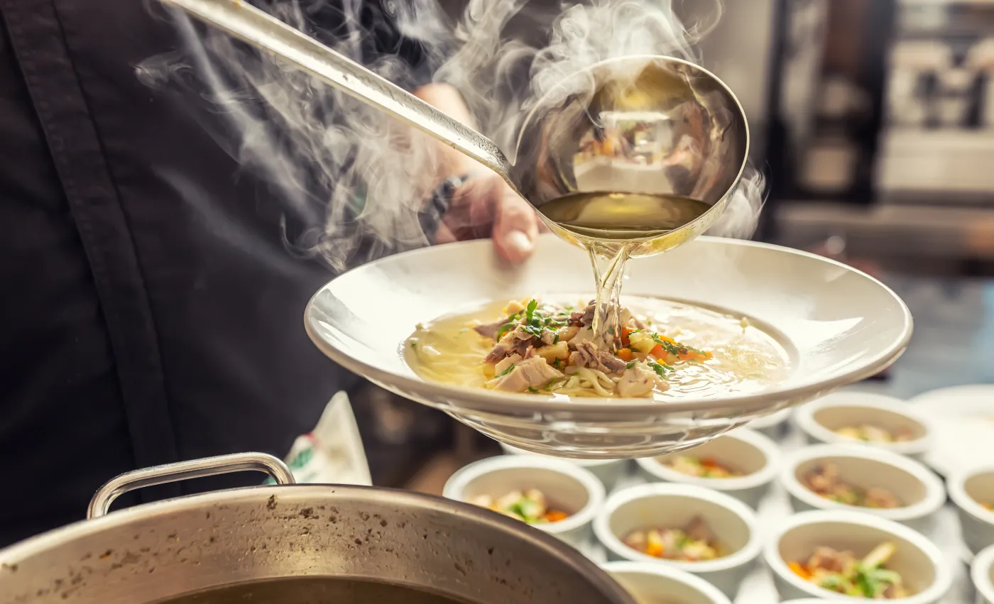 Chef,Pours,Broth,Into,A,Chicken,Soup,With,Noodles,,Meat