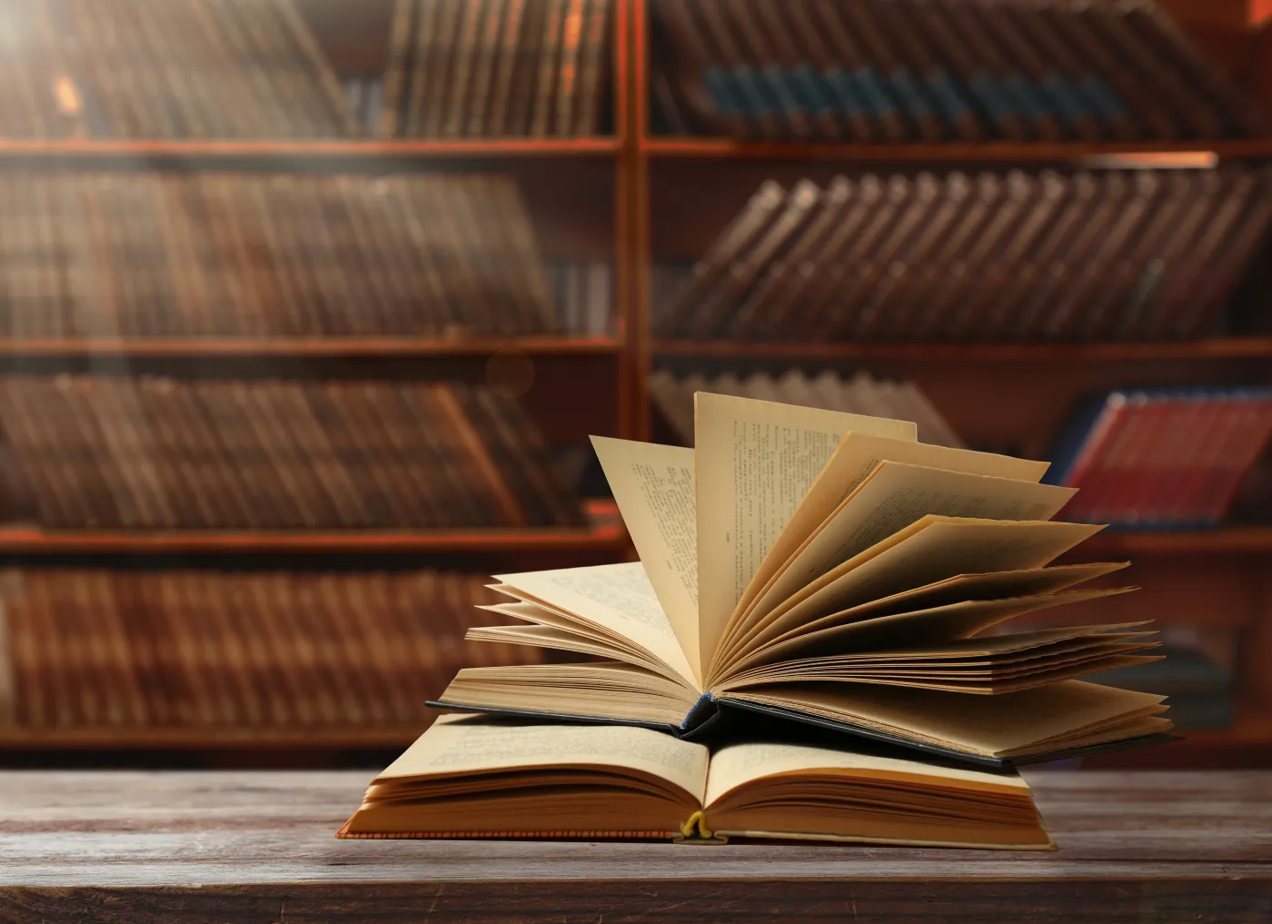 Books,On,Wooden,Table,Against,Full,Shelves,In,Library