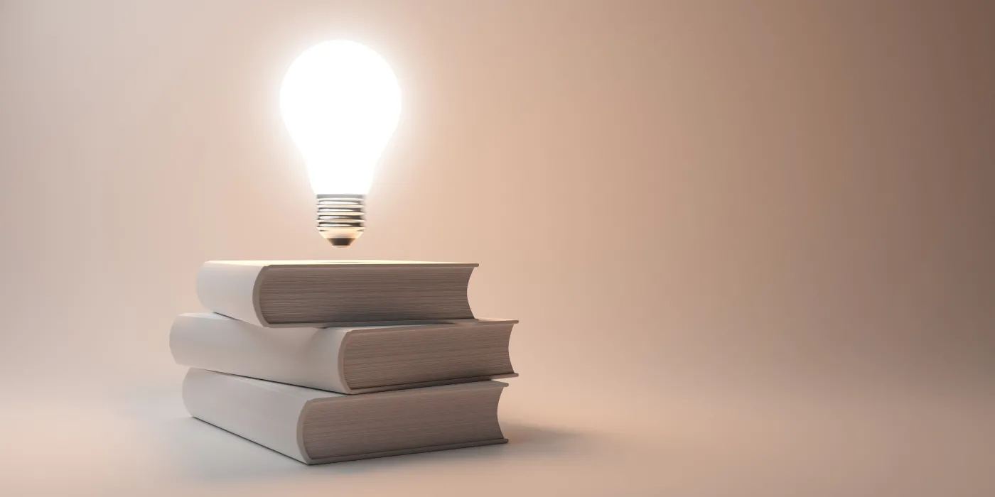 Glowing,Light,Bulb,Floating,Above,Stack,Of,White,Books,Over