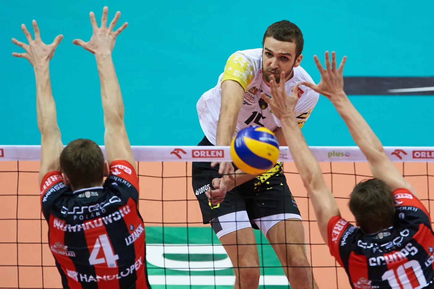 Zawodnik Lotosu Trefl Gdańsk Mateusz Mika (C) atakuje po bloku Piotra Nowakowskiego (L) i Jochena Schopsa (P) z Asseco Resovia Rzeszów podczas meczu finałowego Pucharu Polski siatkarzy