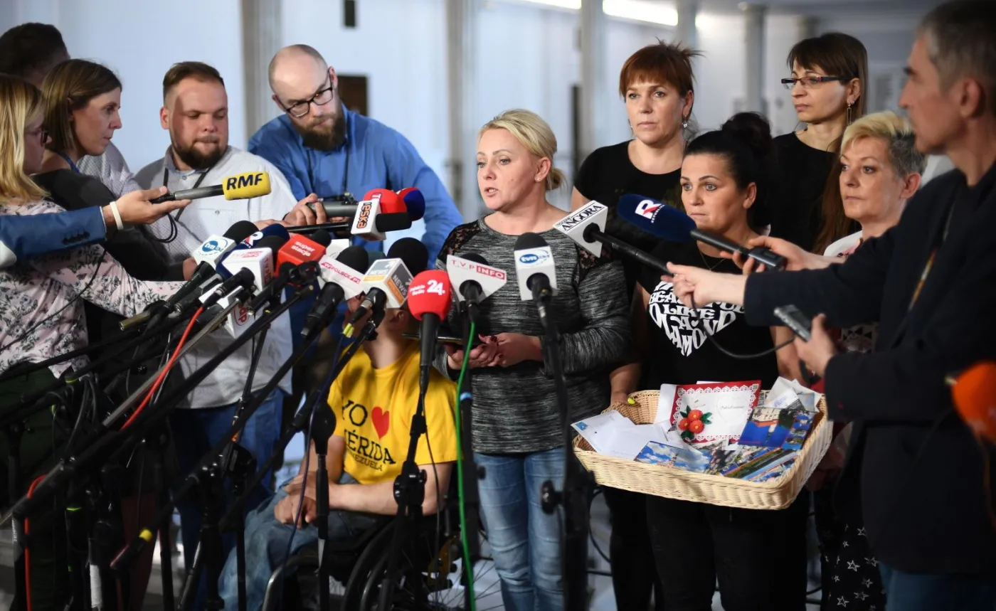 Iwona Hartwich (C) oraz niepełnosprawni i ich opiekunowie podczas konferencji prasowej w Sejmie