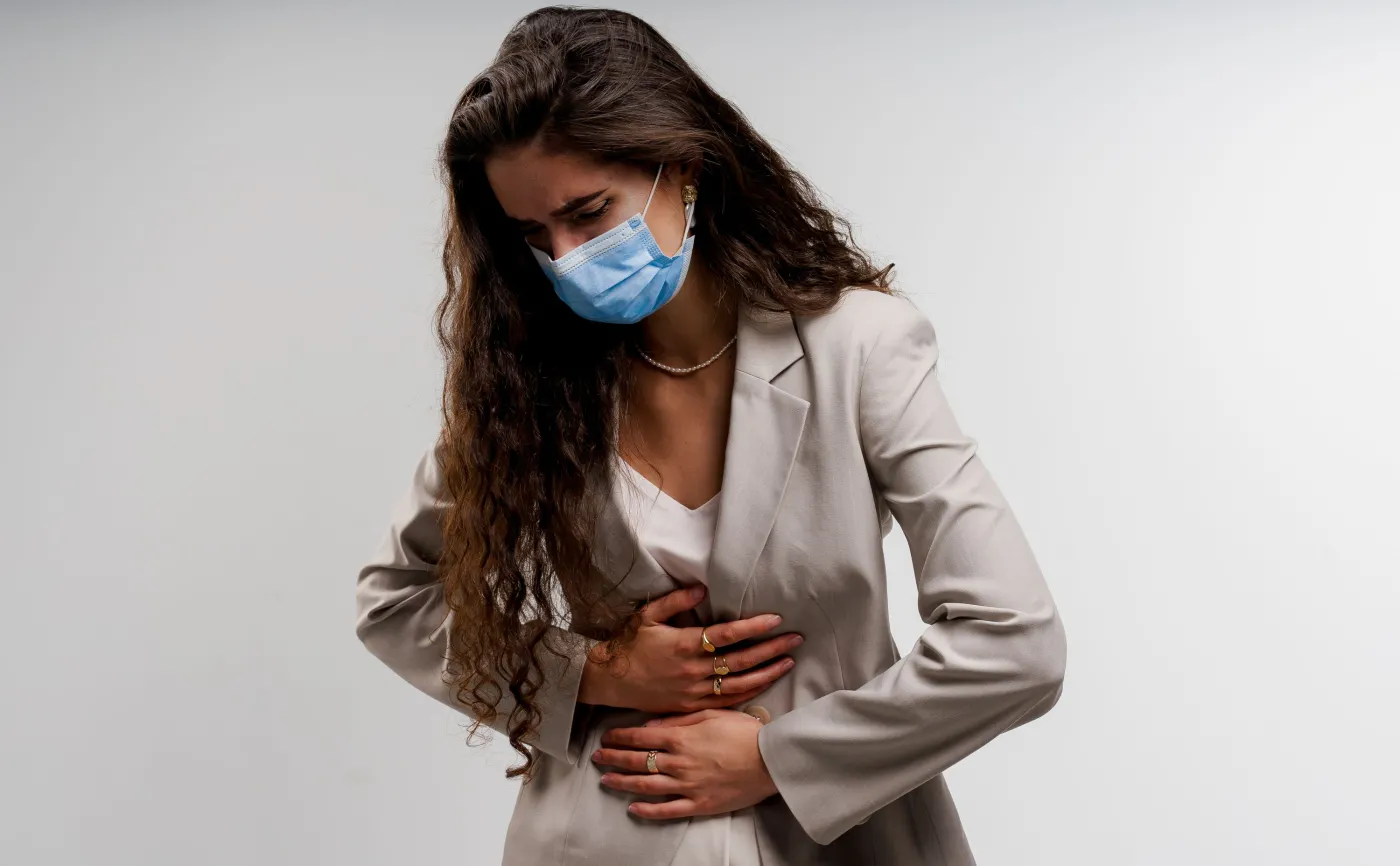 Kobieta obejmuje brzuch, ból żołądka