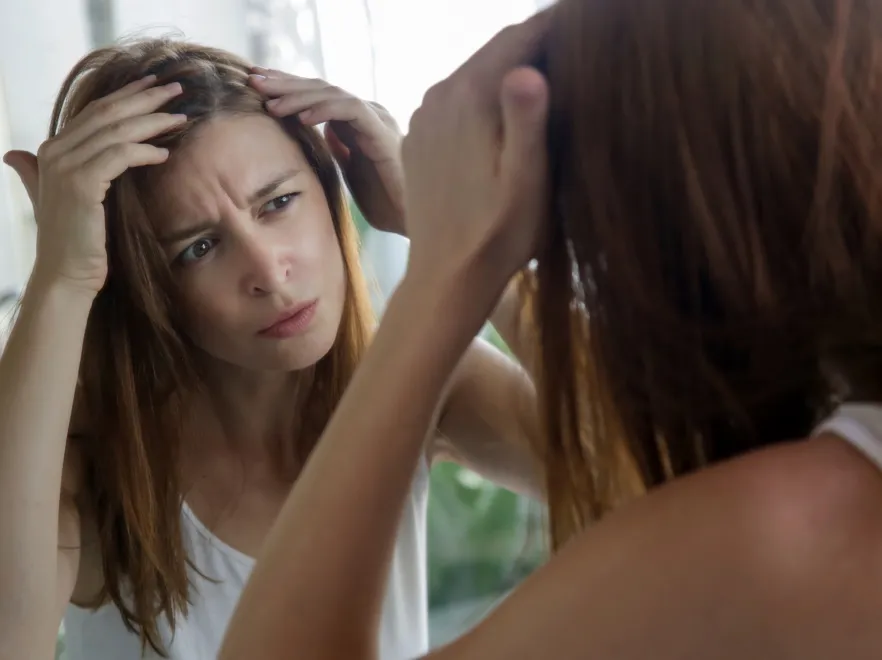 Kobieta ogląda swoje włosy w lustrze