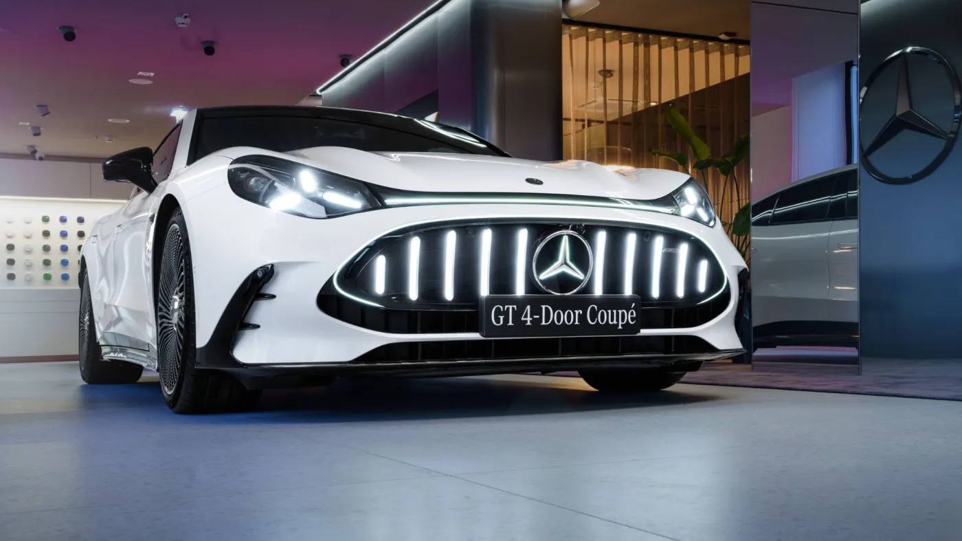 Przód białego elektrycznego samochodu Mercedes-AMG GT 4-Door Coupe z charakterystycznym, pionowo podświetlanym grillem i logo marki w salonie