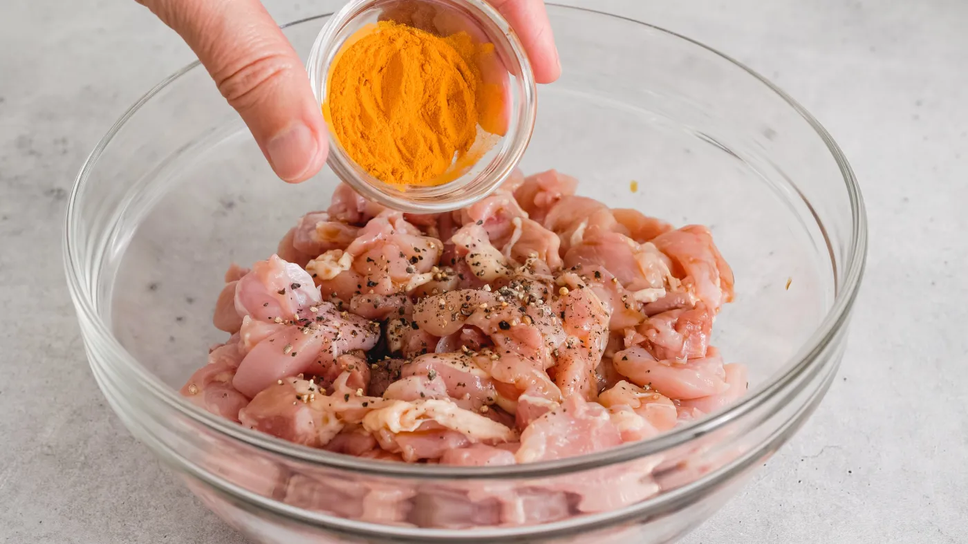 Kurczak marynowany w jogurcie Adding,Turmeric,To,Chopped,Chicken,Fillet,.,Glass,Bowl,With
