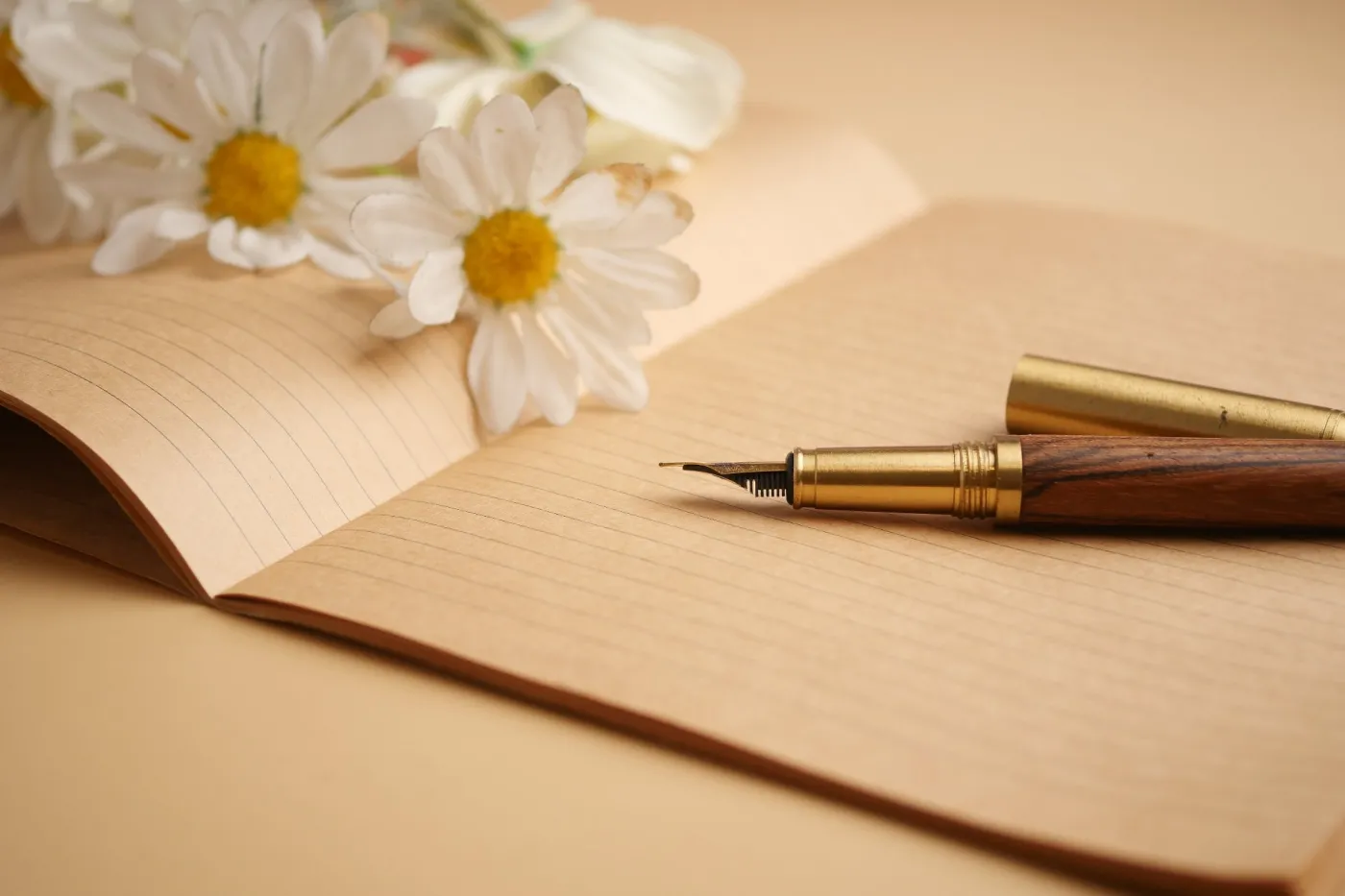 Writing,With,A,Fountain,Pen,Near,Flowers,On,A,Notebook