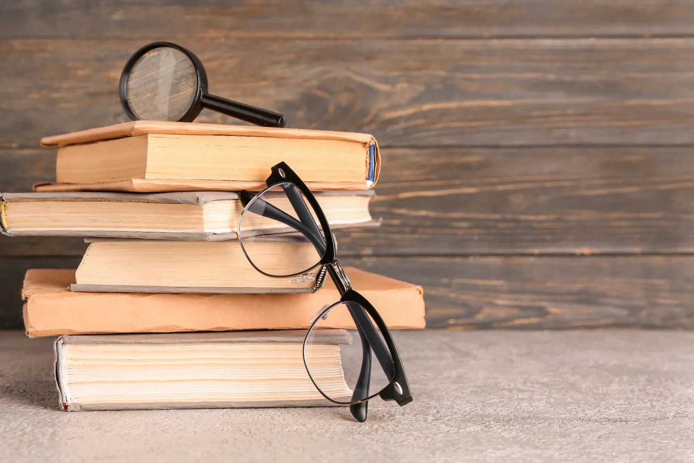 Eyeglasses,With,Stack,Of,Books,And,Magnifier,On,Table,Near