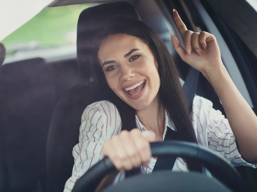 Kobieta kierowca słucha muzyki w samochodzie.