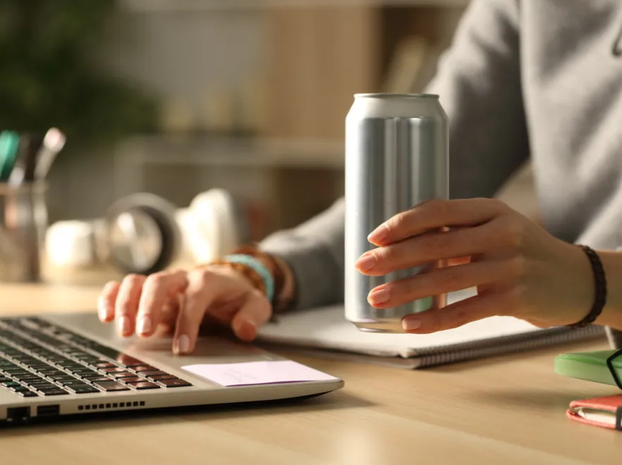 Kobieta przy komputerze pije napój energetyczny