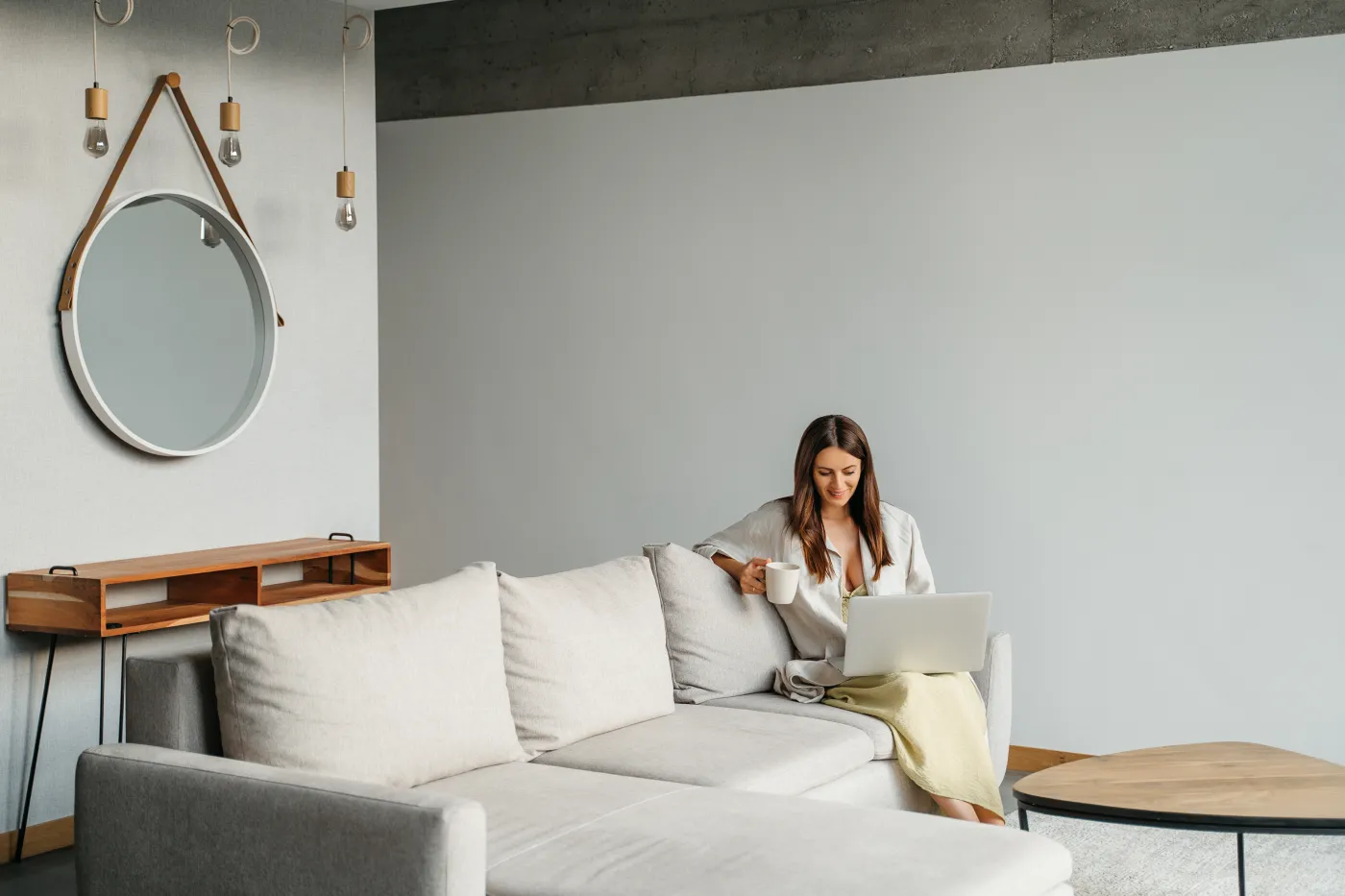 Happy,Smiling,Woman,Sitting,On,Couch,And,Using,Laptop,At