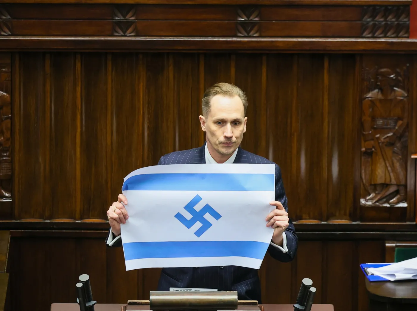 Posel Konfederacji Konrad Berkowicz trzyma flage w barwach Izraela ze swastyka