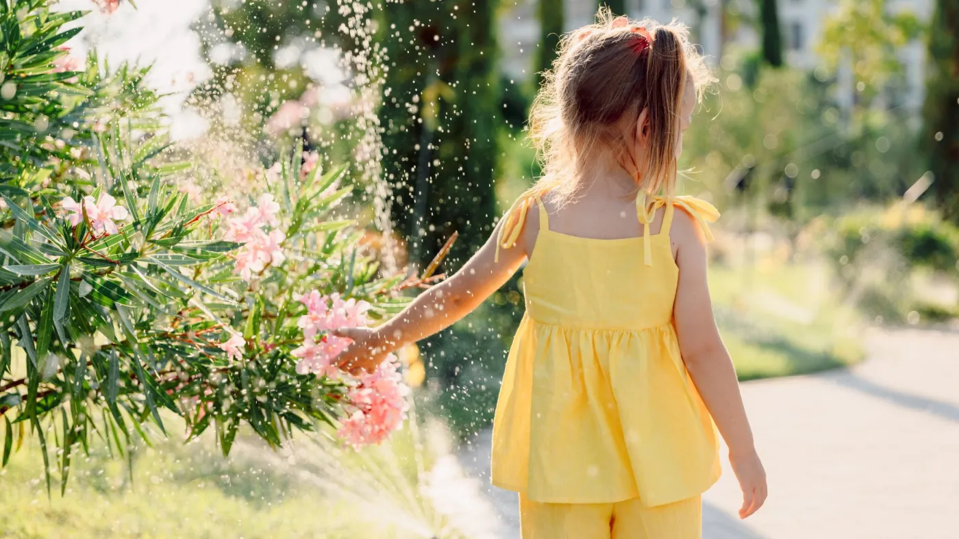 Little,Girl,In,Yellow,Staying,Near,Sprinkler,On,A,Sunny