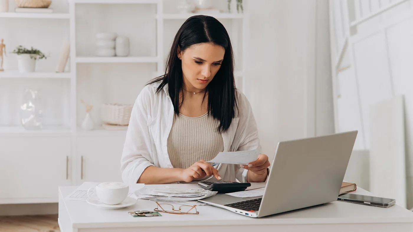 Studentka, młoda kobieta sprawdza paragony i wydatki przy laptopie