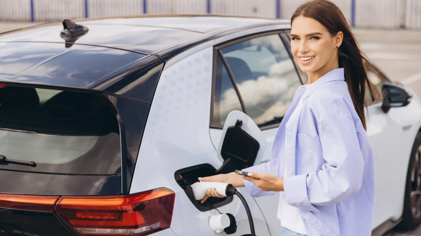 Młoda kobieta podłącza samochód elektryczny do ładowania baterii
