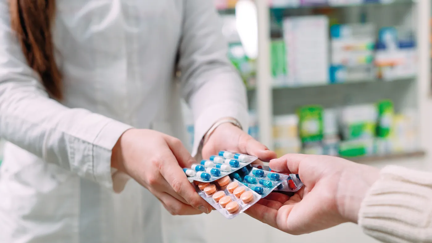 Farmaceuta przekazuje pacjentowi leki w aptece