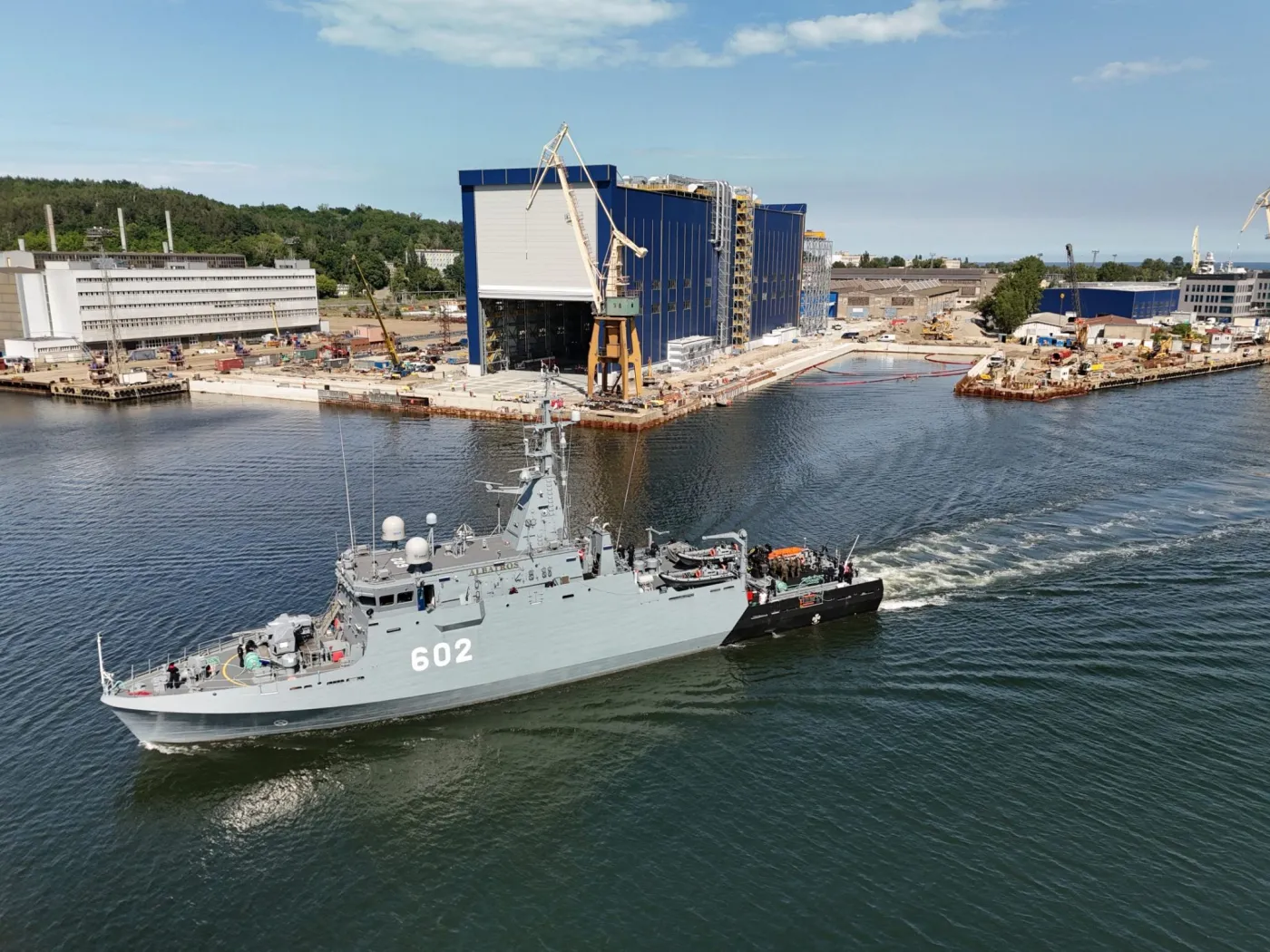 Niszczyciel min ORP Albatros (602) na tle hali w której powstanie ORP Wicher (pierwsza polska fregata zamówiona w ramach programu Miecznik).