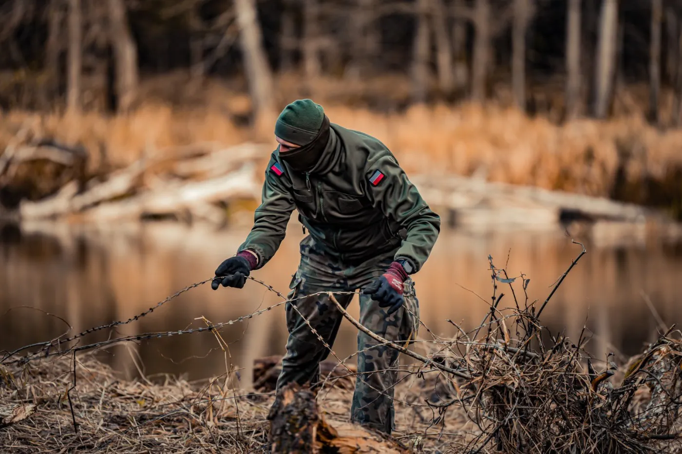 Żołnierz podczas demontażu zapory tymczasowej na rzece Bug. Ubrany jest w zieloną zielony ocieplacz softshell (wz. 128Z MON). W połączeniu z kurtką przeciwdeszczową tworzą one kurtkę zimową.