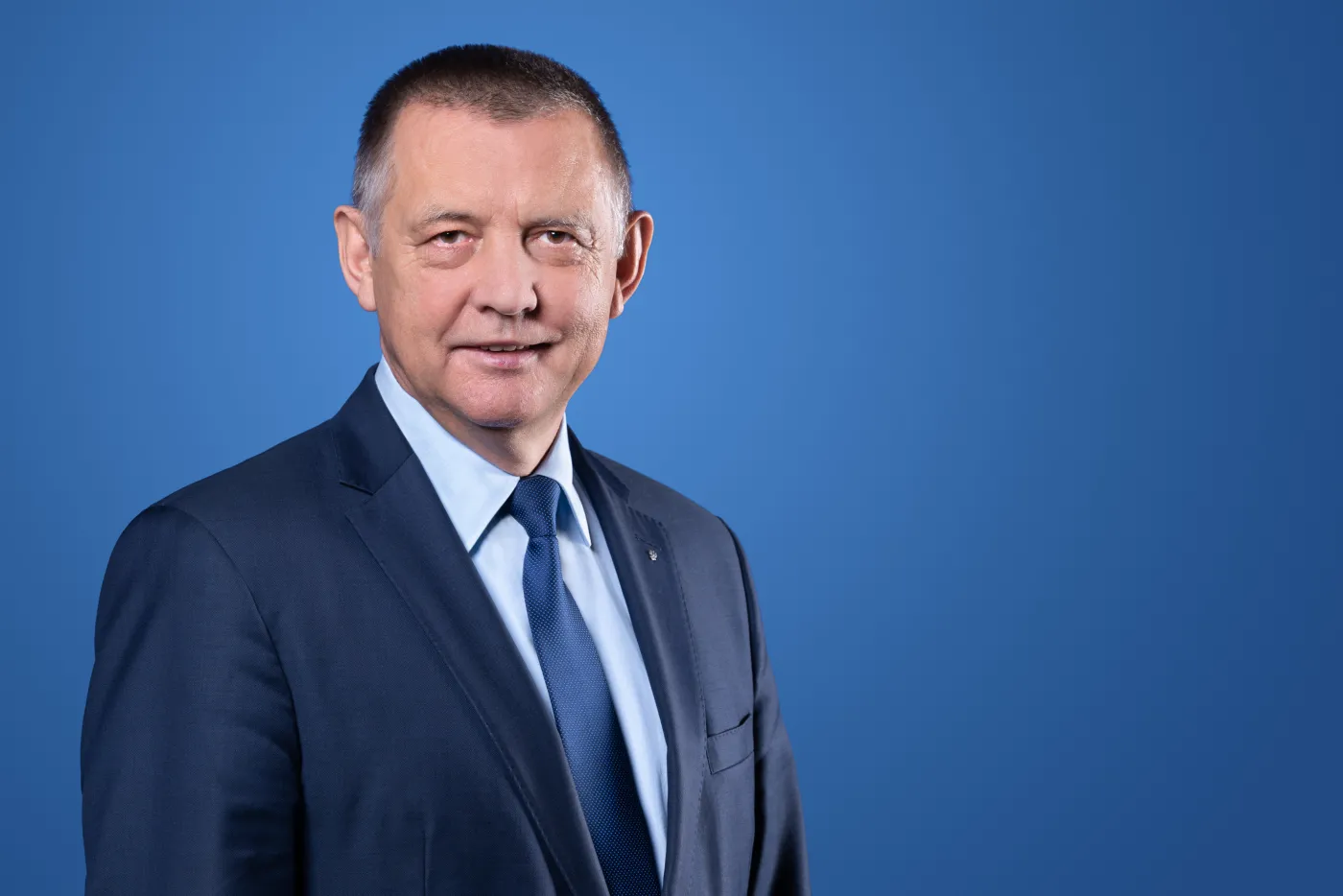 Prezes Najwyższej Izby Kontroli (NIK) Marian Banaś na niebieskim tle.