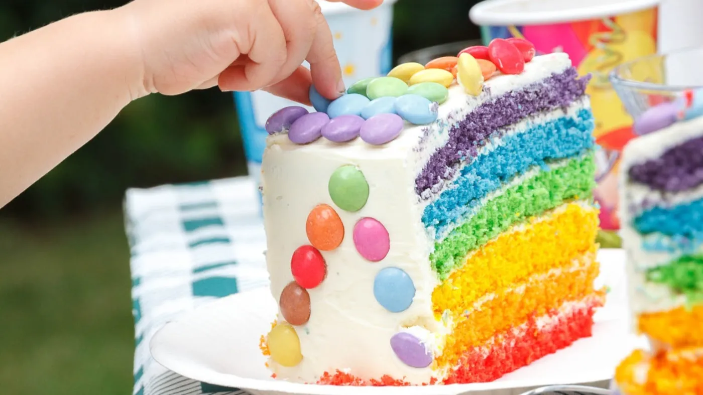 Ręka dziecka dotyka kolorowego tortu