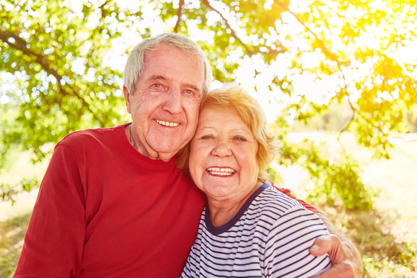 Para uśmiechniętych seniorów obejmuje się w plenerze