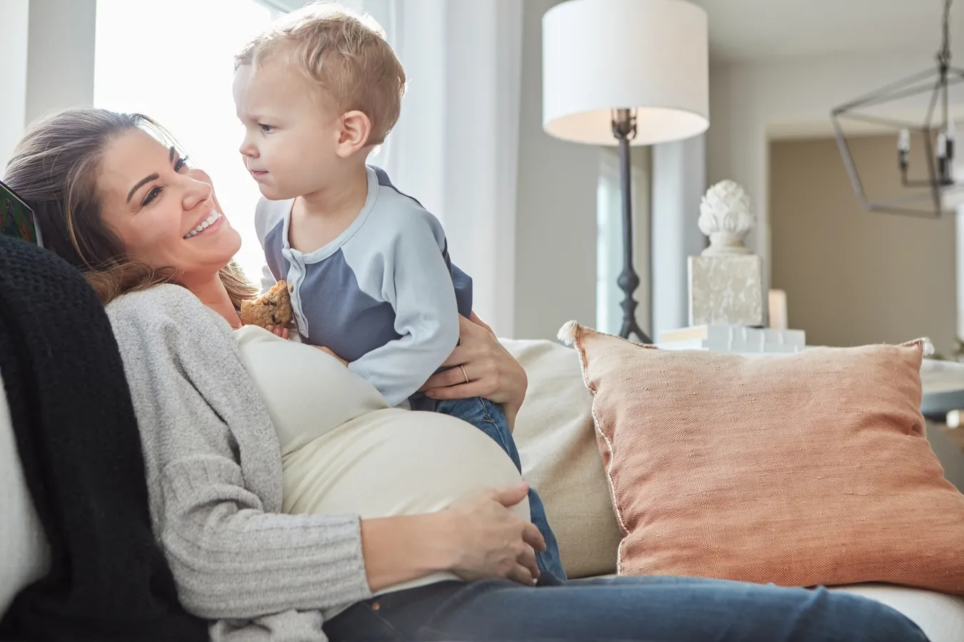 Szczęśliwa mama w ciąży z dzieckiem na tle nowo wybudowanego domu – spłata rodzinna w 2026 roku.