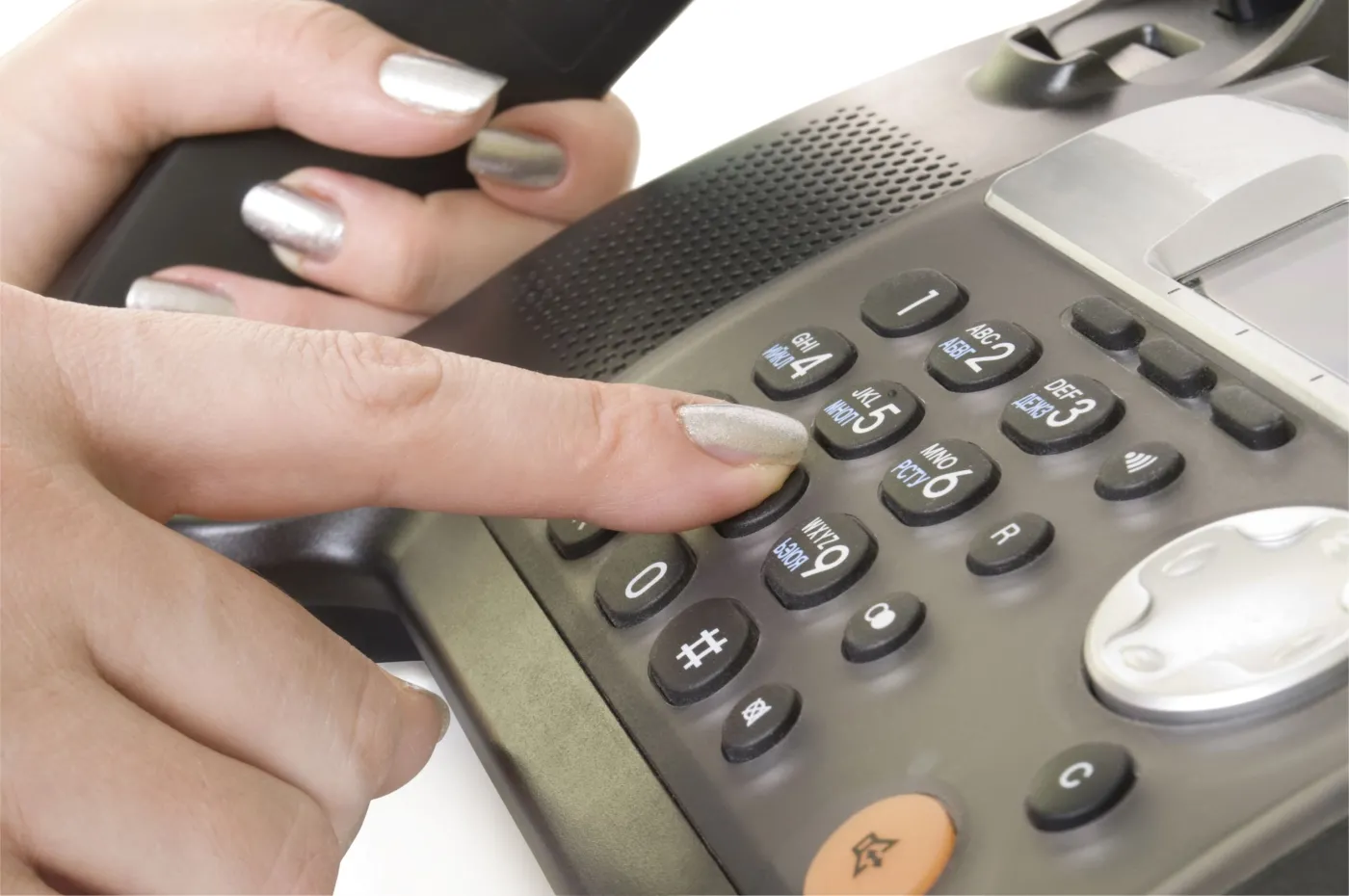 Kobieta wybiera numer w telefonie stacjonarnym