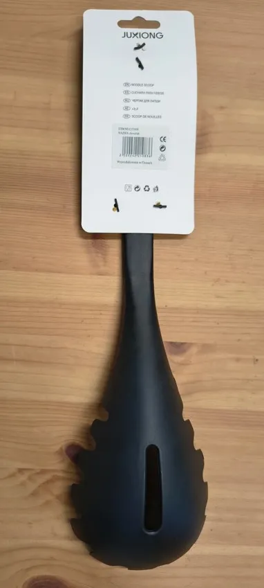 Czarna plastikowa łyżka do makaronu marki JUXIONG z białą etykietą produktową, objęta ostrzeżeniem GIS dotyczącym toksycznych amin aromatycznych