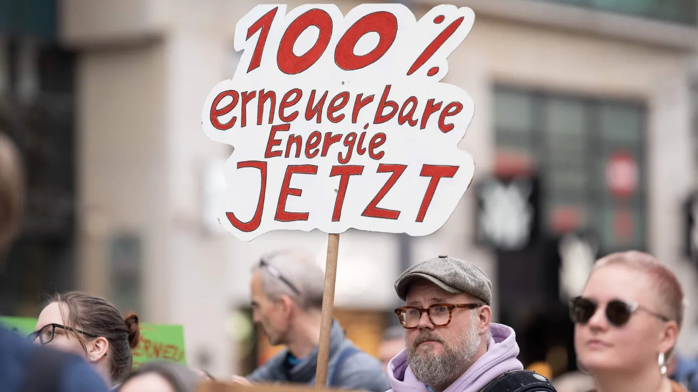 Grupa protestujących przeciwko polityce energetycznej rządu Friedricha Merza. Hamburg, kwiecień 2026 r. Na pierwszym planie mężczyzna z transparentem
