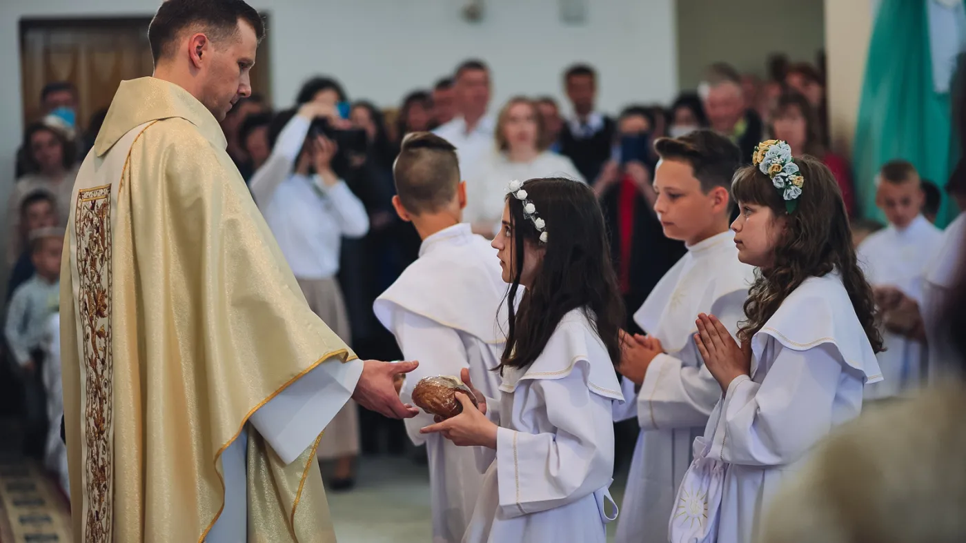 Ksiądz, dzieci i rodzice podczas komunii
