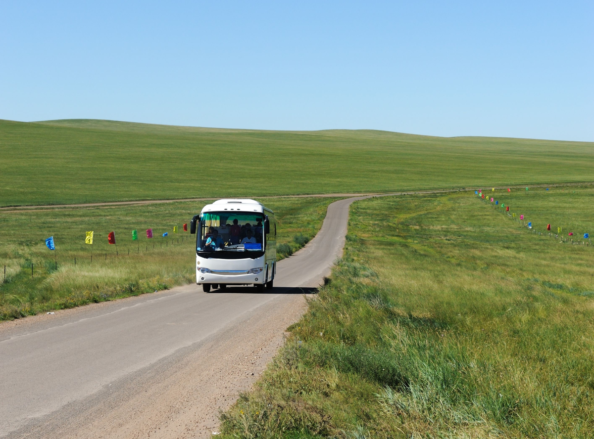 autobus na wiejskiej drodze, dookoła zielone łąki